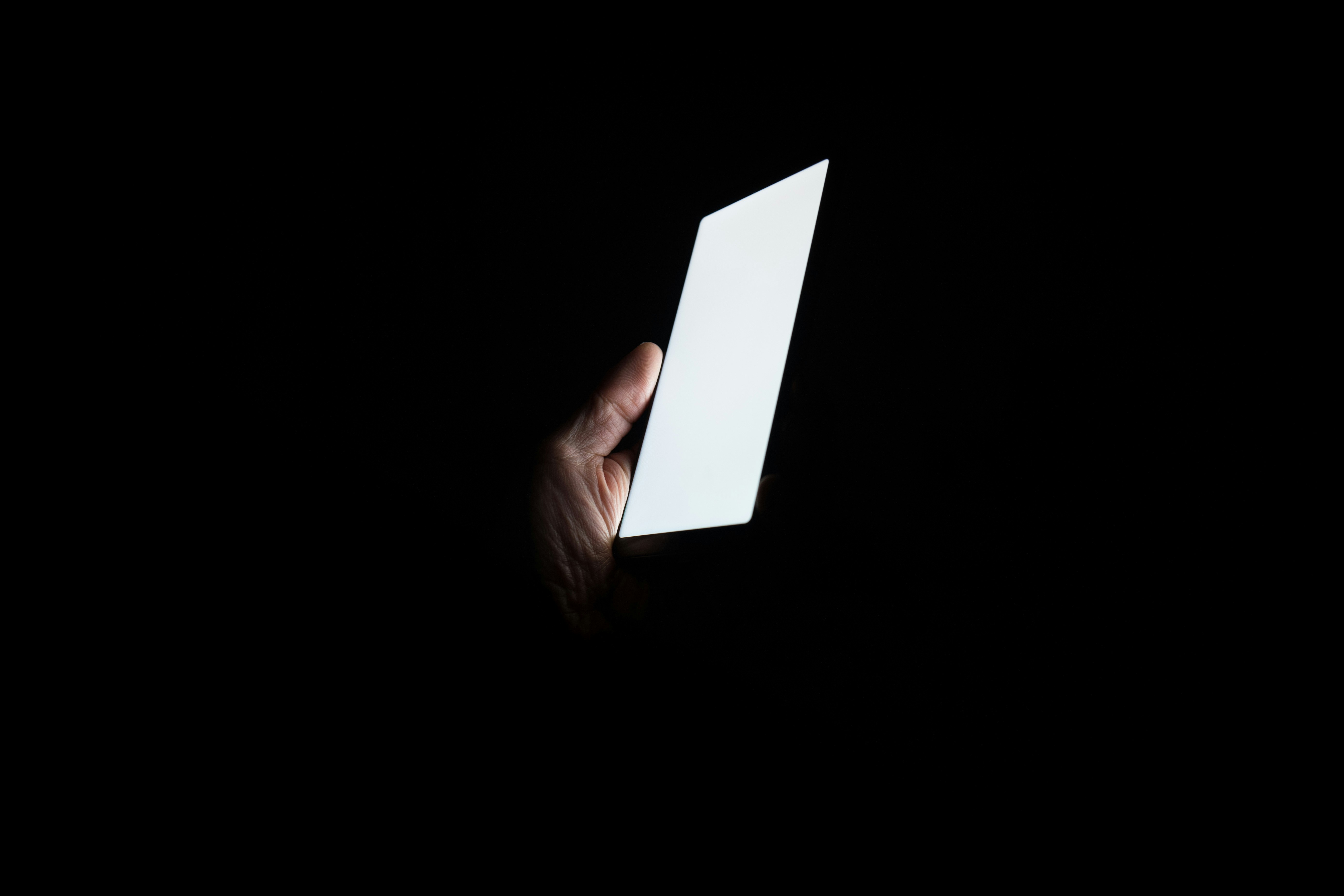 Persona sosteniendo el celular de noche con la pantalla iluminada, representando un mensaje que llega fuera del horario de atención