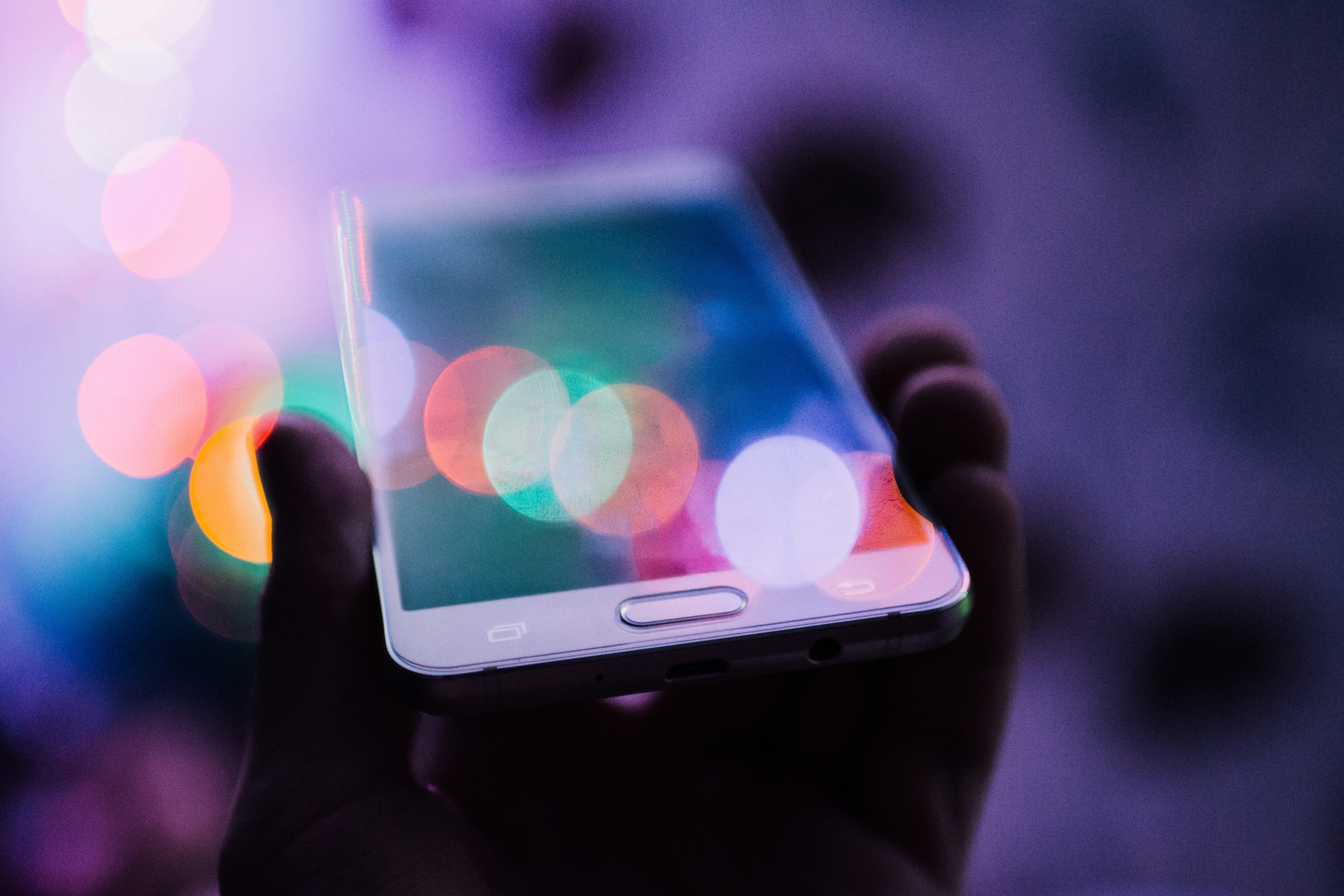 Celular con la pantalla iluminada en la oscuridad, sostenido en la mano