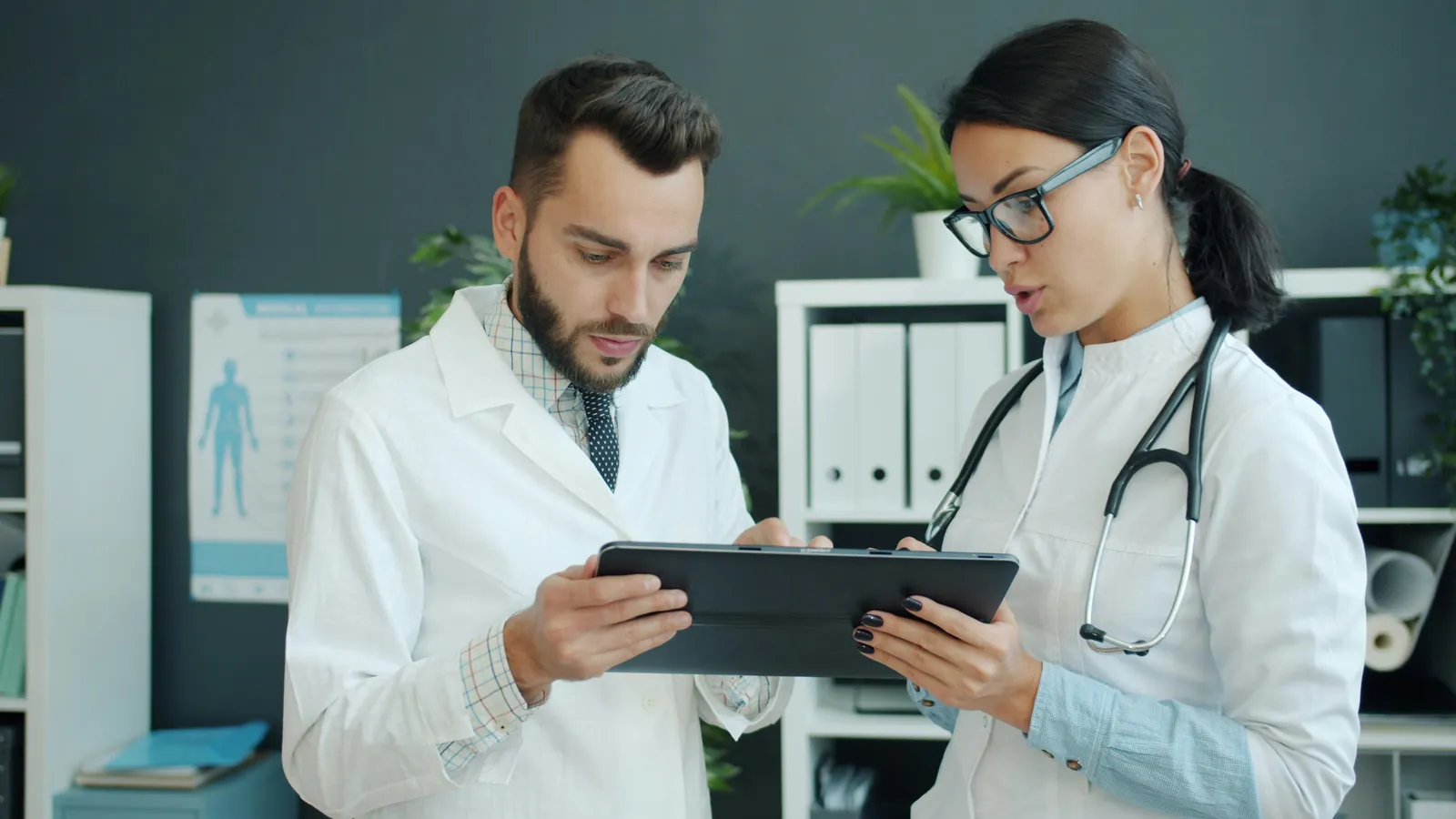 Dos médicos de una clínica mediana revisando información juntos en una tableta